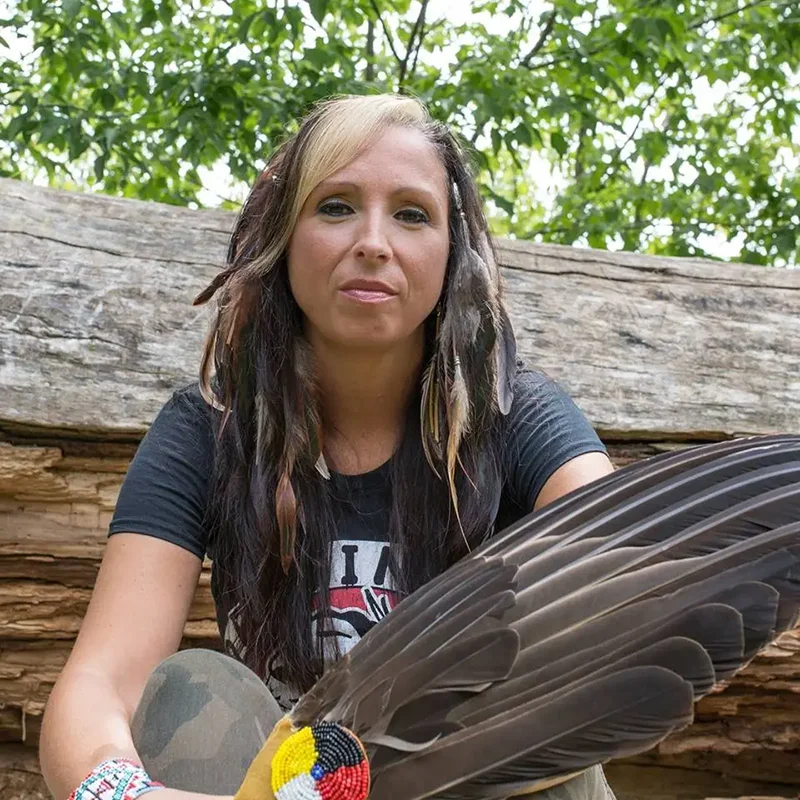 Pam Palmater holding a large brown feather.